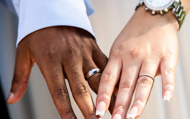 Two hands held side by side showing new wedding bands