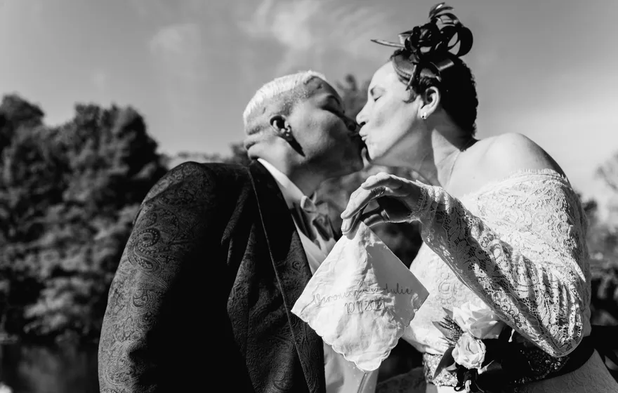 Black and white close-up of two spouses kissing, one holding a bouquet, at a vow renewal