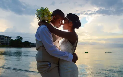 A bride and groom embrace forehead to forehead on a Caribbean beach at sunset