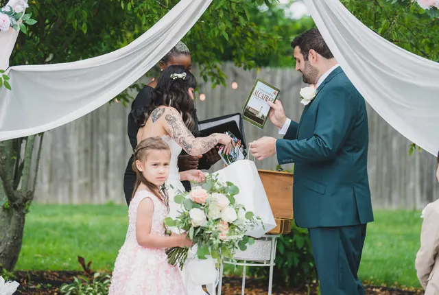 A couple unpacking their unity ritual keepsakes under draped fabric at a backyard ceremony